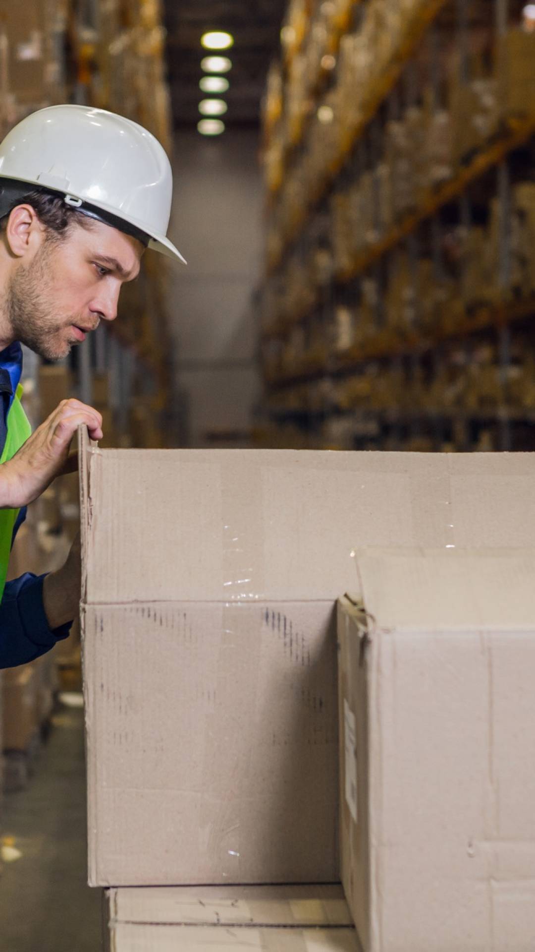 Worker checking boxes with merchandise in warehouse